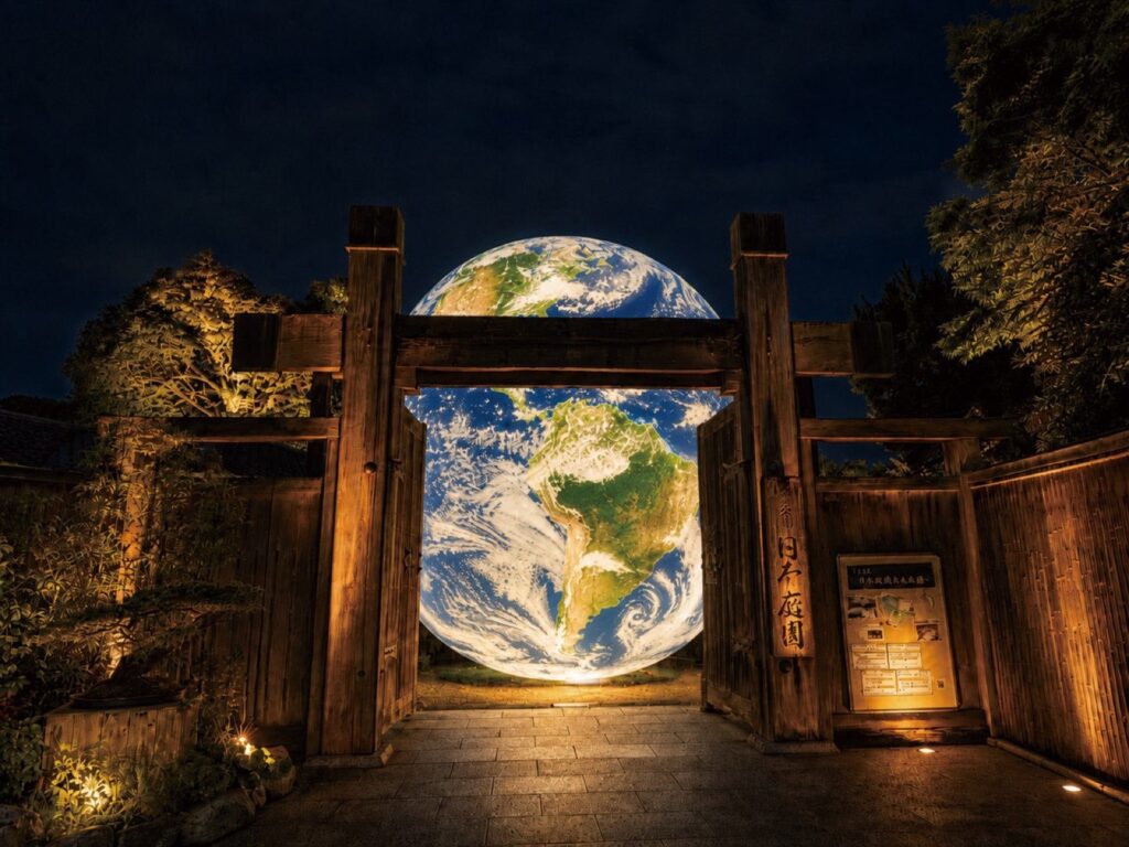 【ナイト】大濠公園日本庭園の光の展示「世解」 コンテンツ「世界(光る地球)」。日本庭園の門に浮かぶ光る地球の演出(人物なし)