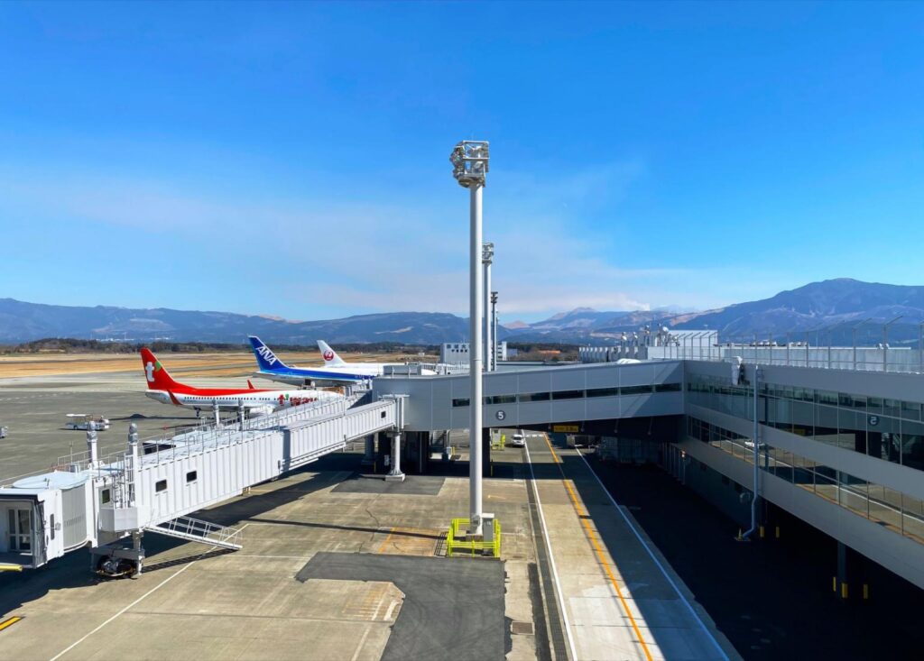Aircraft at the gates of Aso Kumamoto Airport, with mountains behind